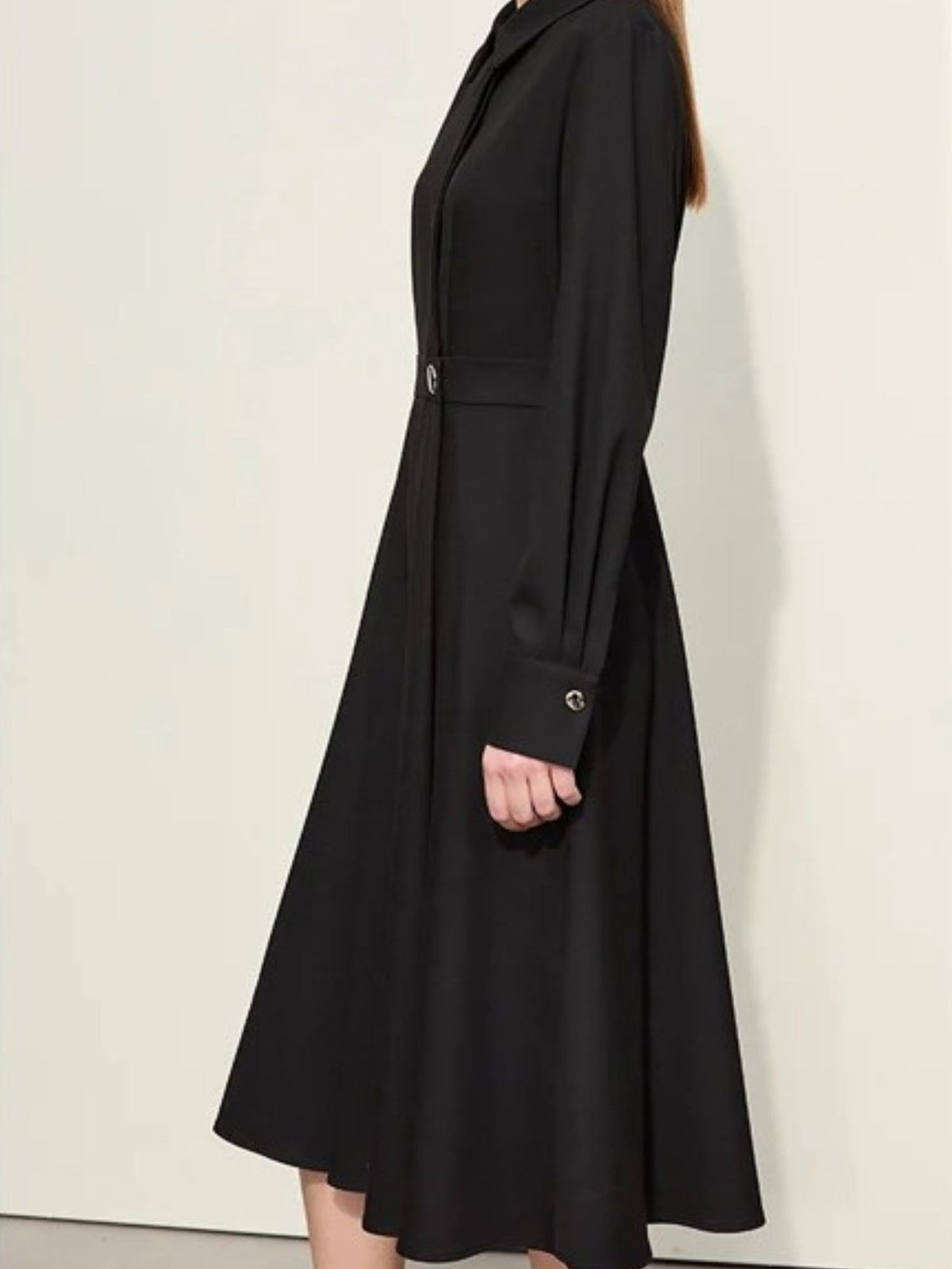 Angled back view of black buttoned dress with pleated skirt and midi length