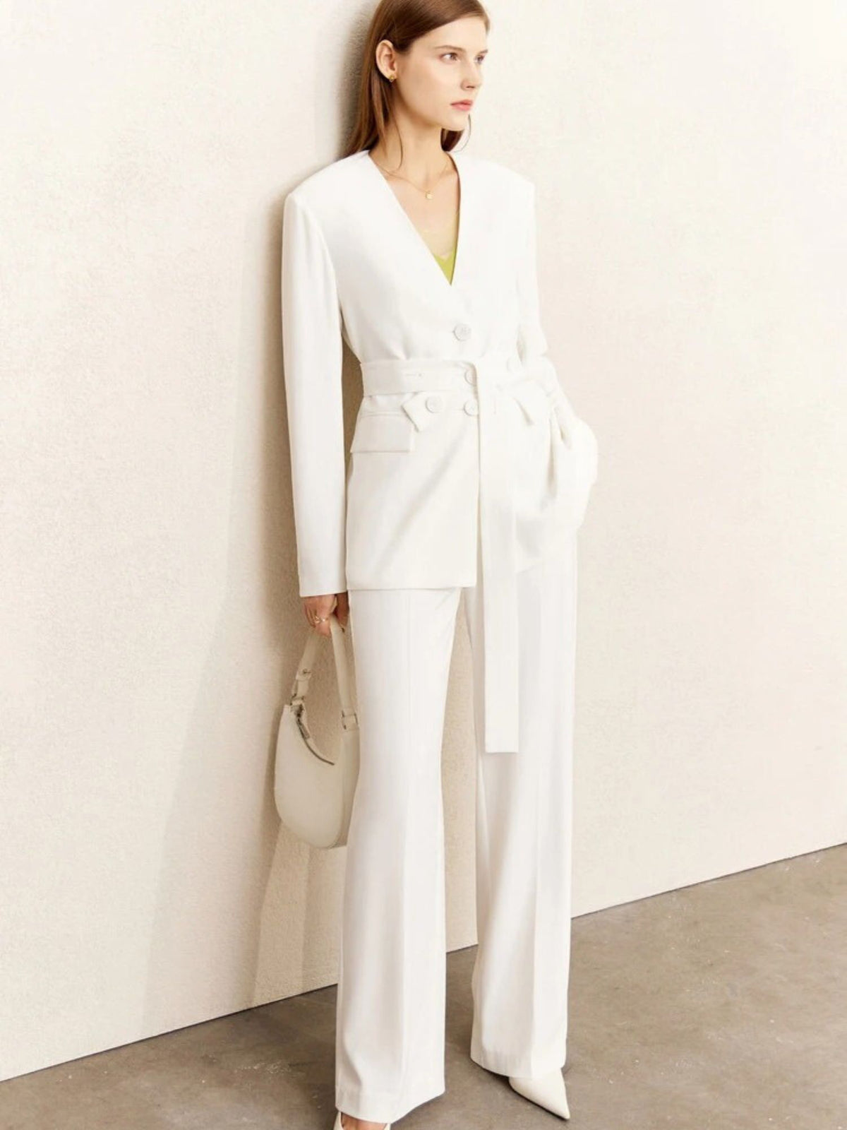 White pantsuit with tied waist and flap pockets, styled with cream clutch bag