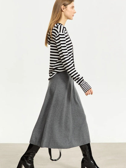Side view of grey A-line midi skirt with soft drape, styled with striped top and black boots