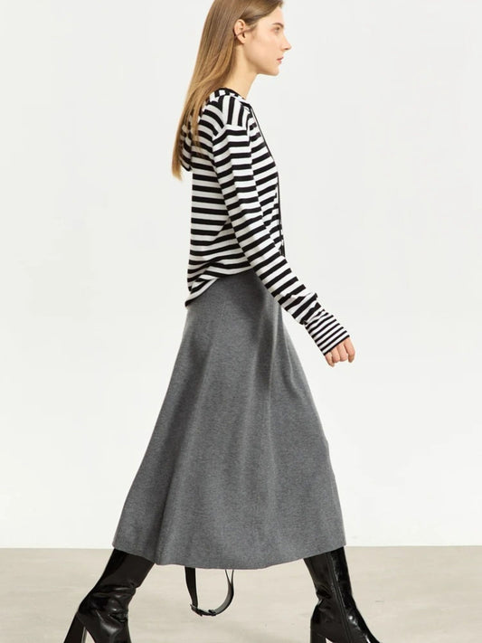 Side view of grey A-line midi skirt with soft drape, styled with striped top and black boots