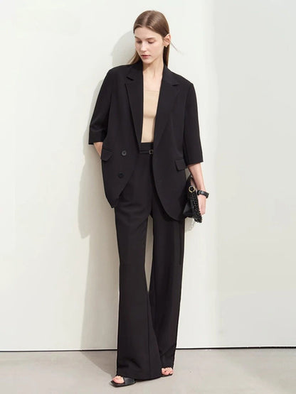 Black oversized blazer with wide-leg trousers, styled with beige top and heeled sandals

