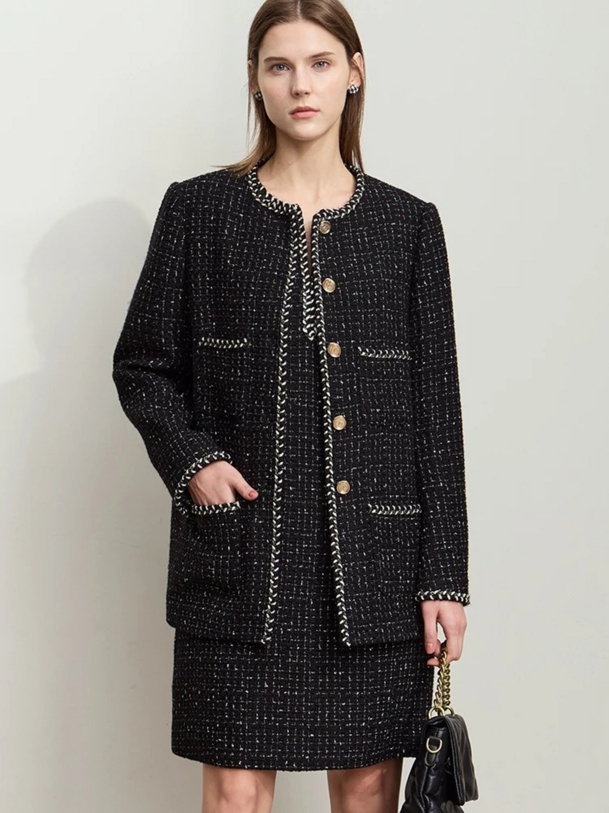 Front view of black tweed jacket with gold buttons and patch pockets, styled with matching skirt