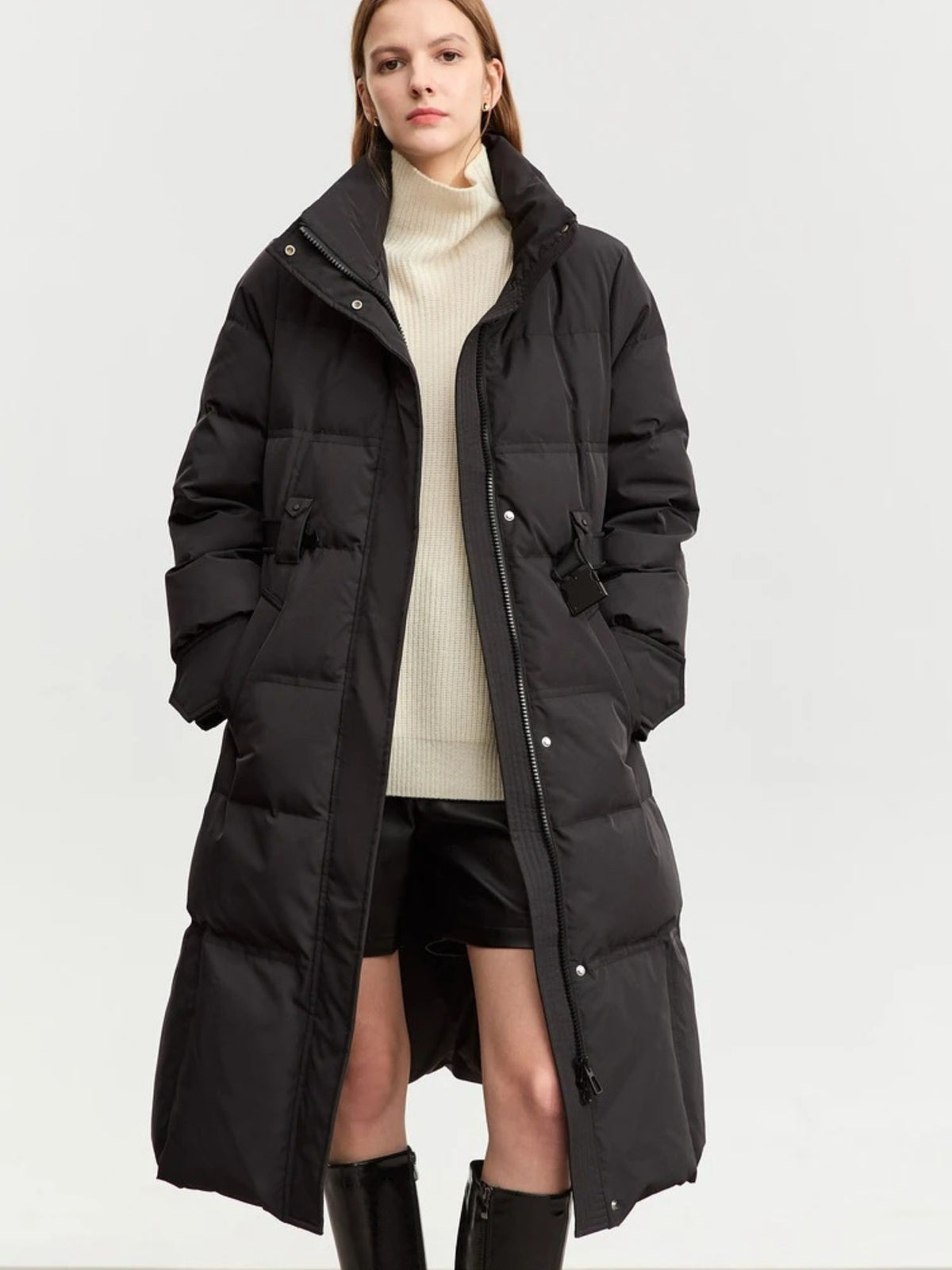 Front view of black puffer coat with oversized fit and hood, styled with cream turtleneck