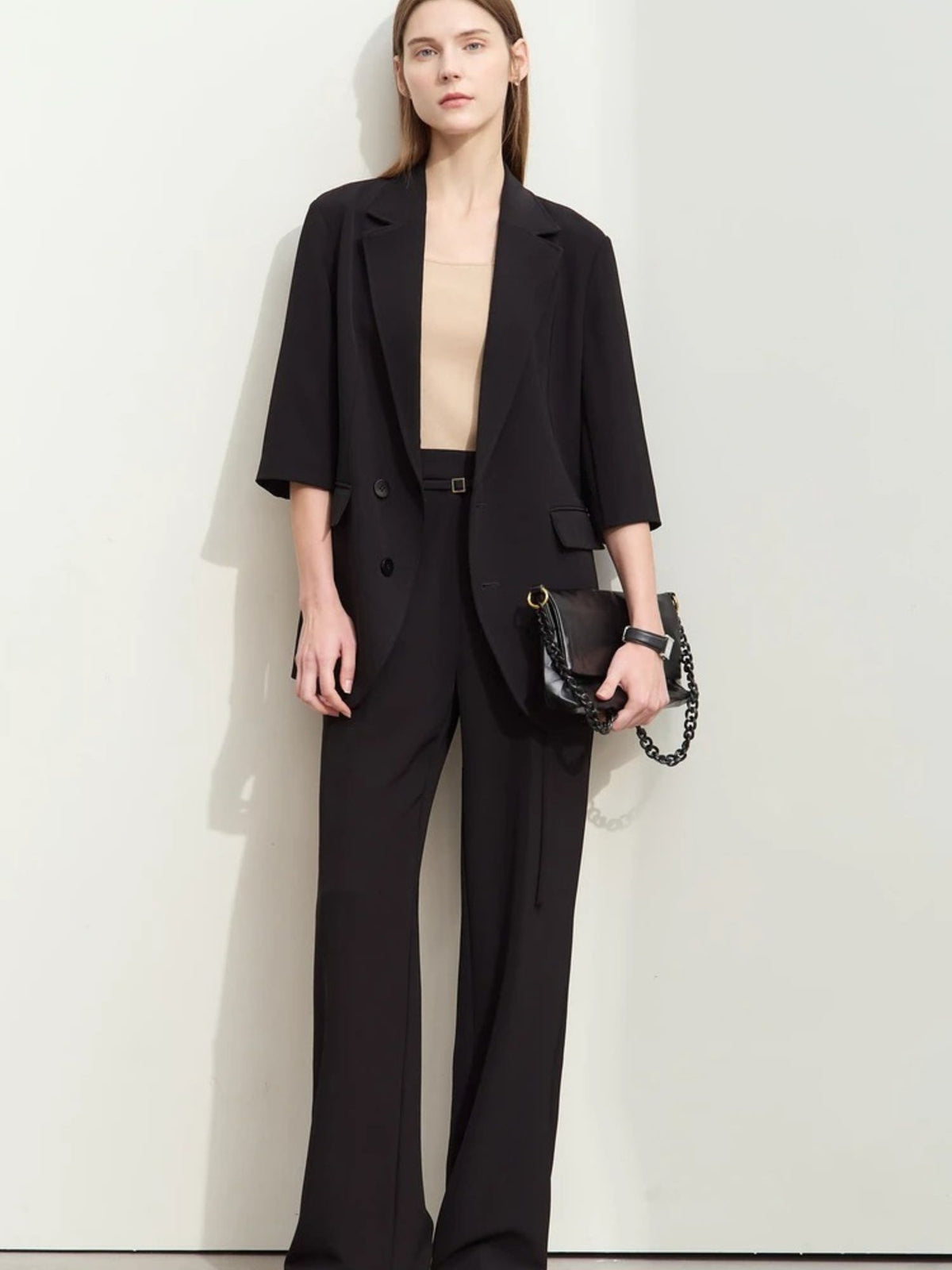 Front view of flowy black pantsuit with soft tailoring, worn with minimal accessories