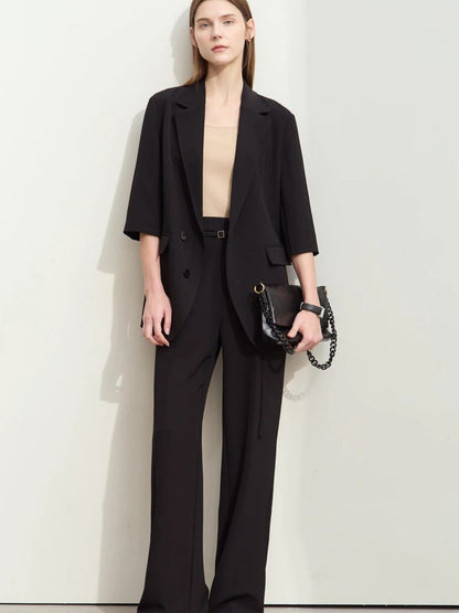 Front view of flowy black pantsuit with soft tailoring, worn with minimal accessories