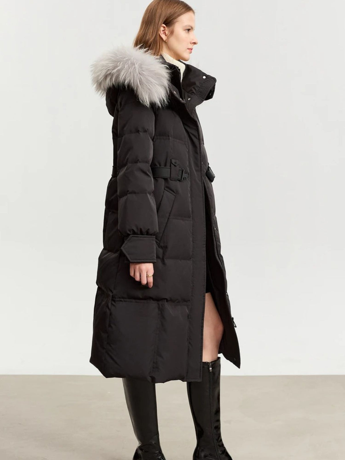 Side view of black puffer coat with silver fur hood, showing belt and length