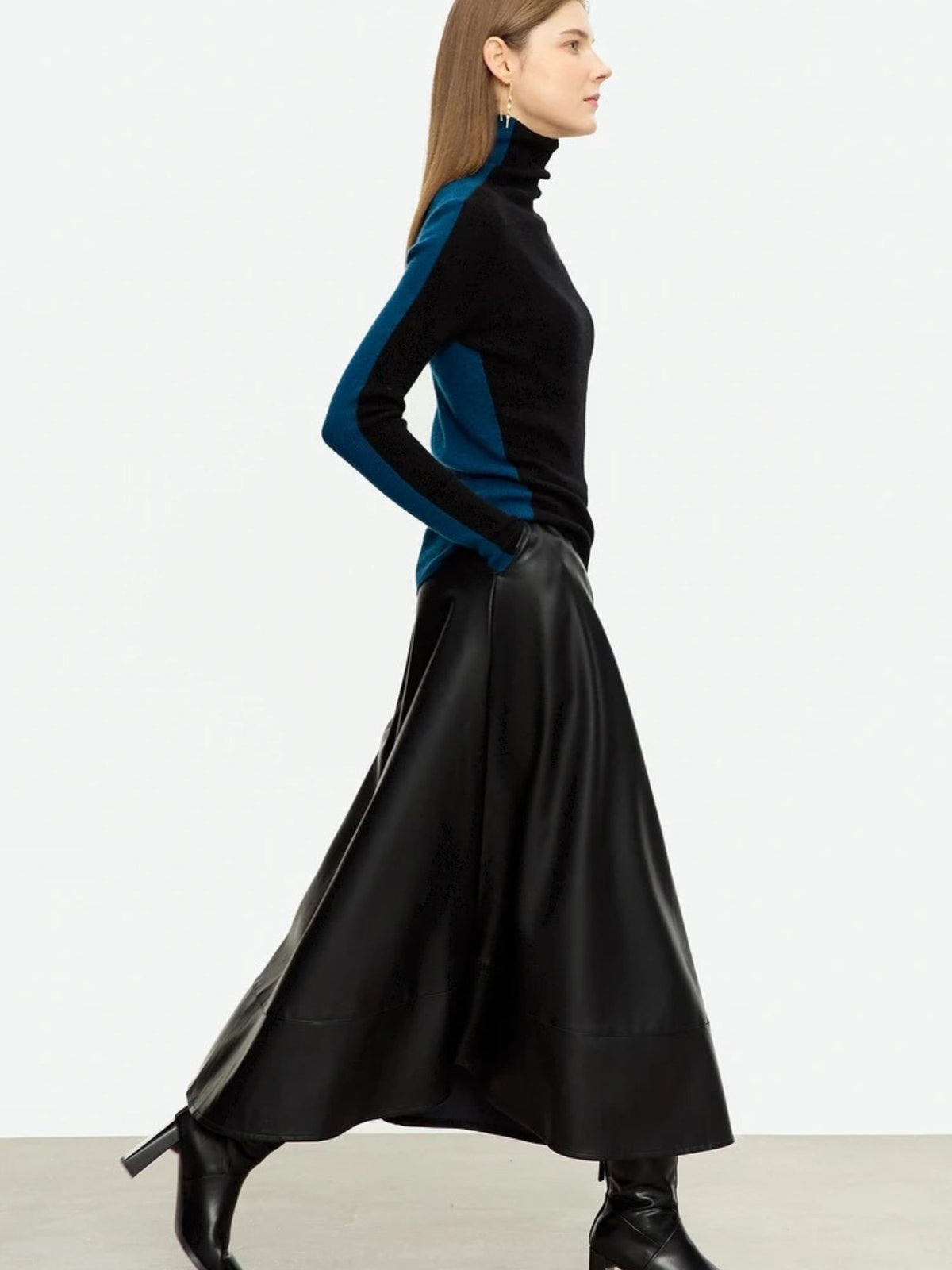 Side view of flowy black midi skirt in motion, worn with fitted top and boots