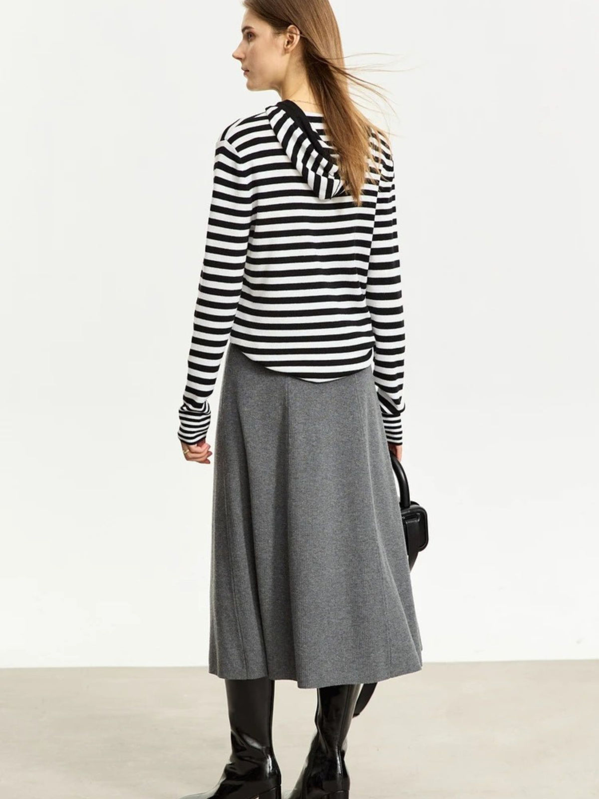 Front view of grey midi skirt with flared silhouette, worn with long-sleeve striped sweater
