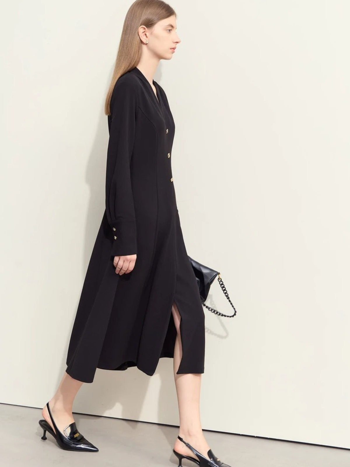 Side view of black button-front dress with midi hem and minimal accessories

