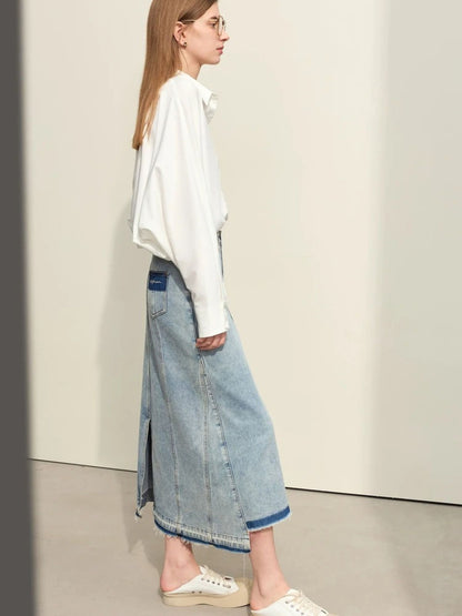 Side profile of light denim skirt with front slit, worn with white sweatshirt