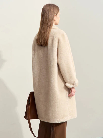 A female model wearing a beige faux fur double-breasted winter coat with a turn-down collar and raglan sleeves facing away.