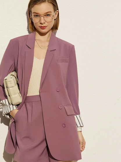 Front view of dusty rose blazer and shorts with striped cuff detail and beige handbag