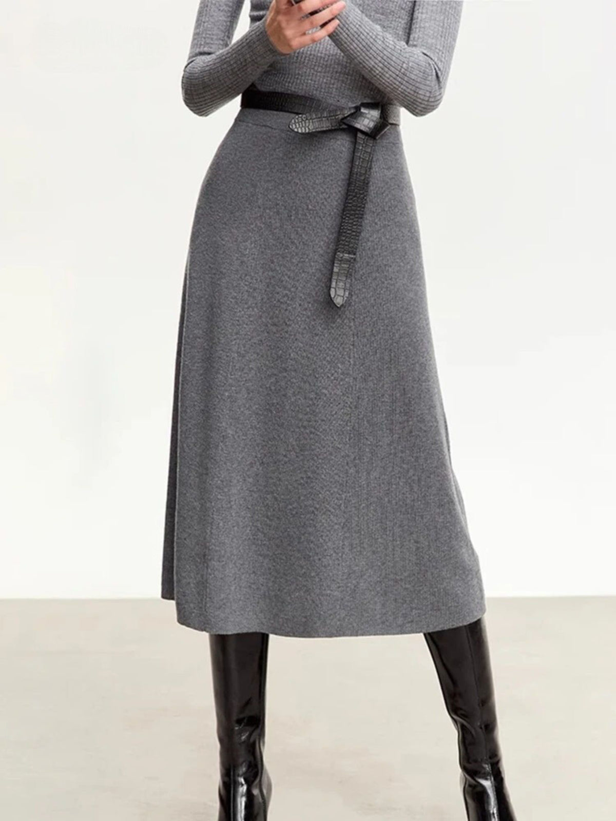 Full-body view of ribbed grey knit skirt with high waist and black ankle boots