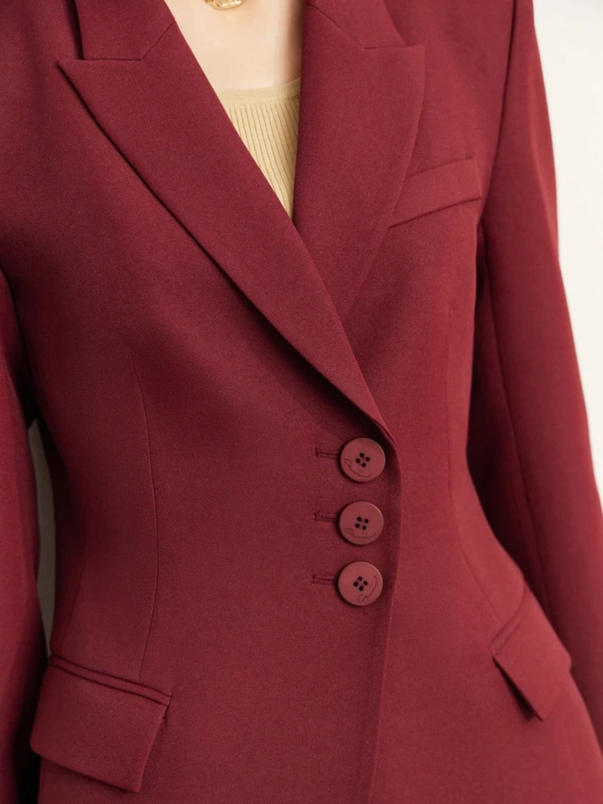 Close-up of burgundy blazer with buttons and sharp tailoring details