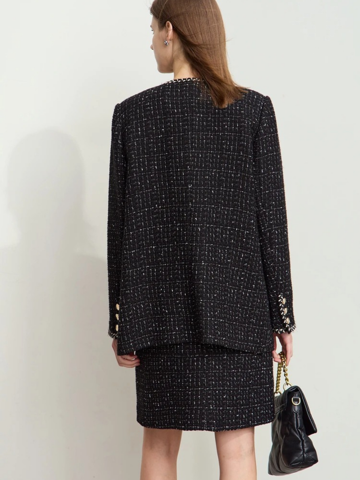 Back view of black tweed jacket with relaxed fit, paired with matching skirt