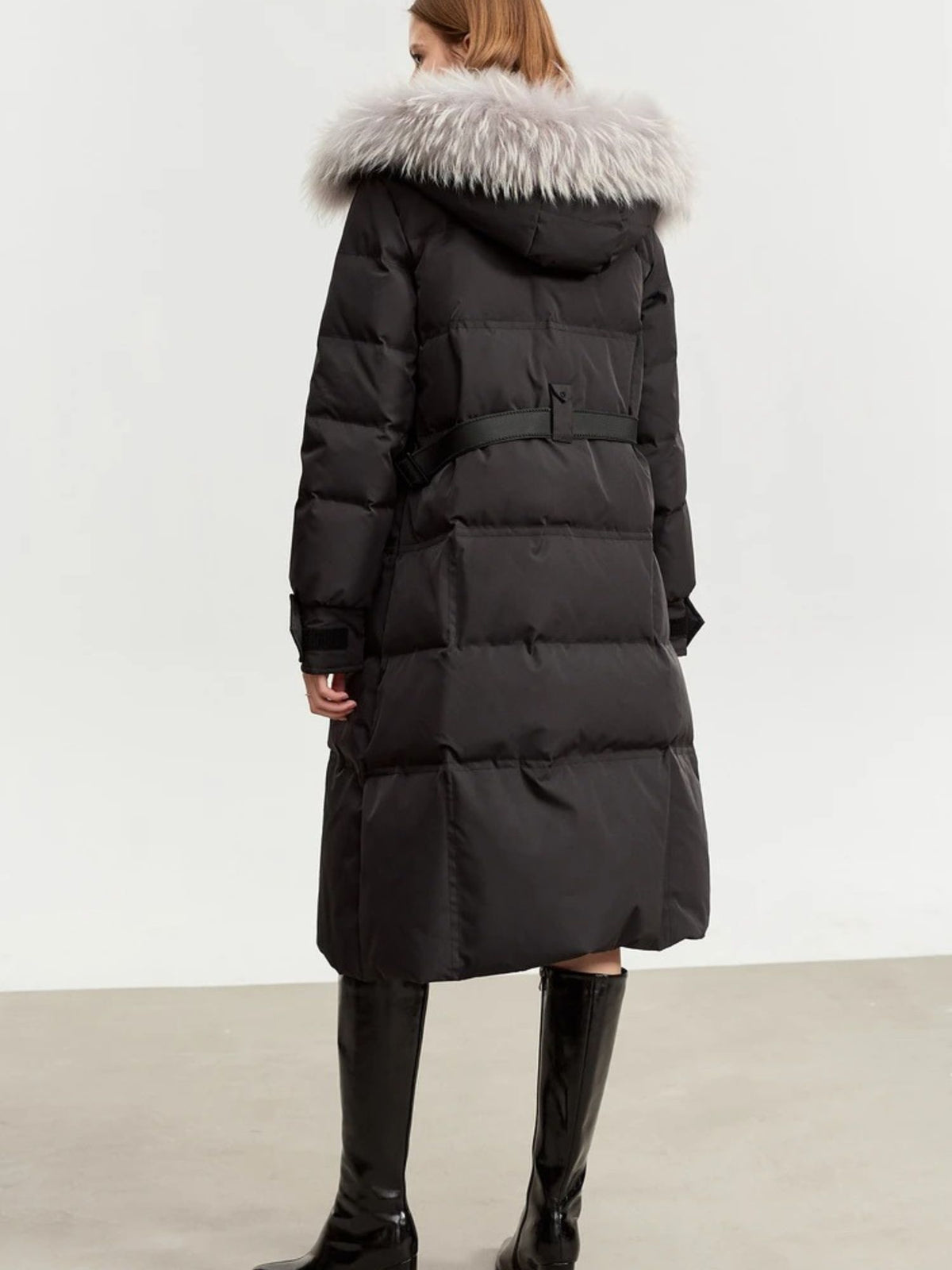 Back view of long black puffer coat with fur-lined hood
