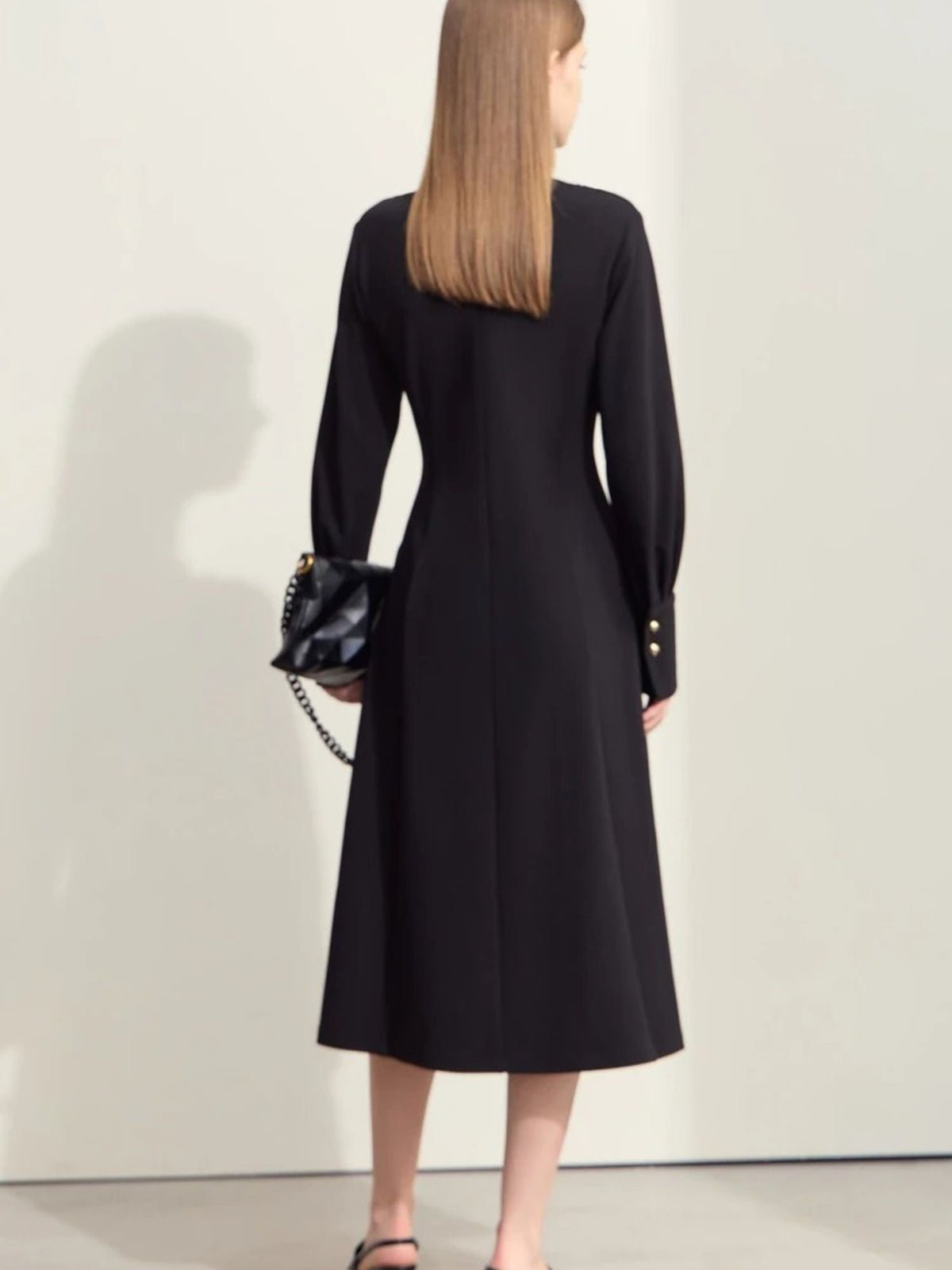 Back view of black v-neck midi dress with long sleeves and flowy skirt