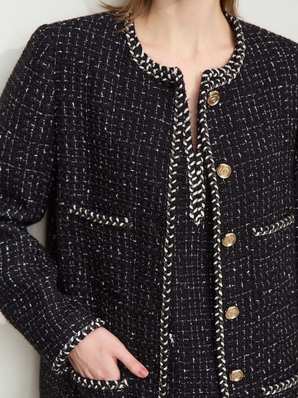 Close-up of black tweed fabric with gold trim and embossed buttons