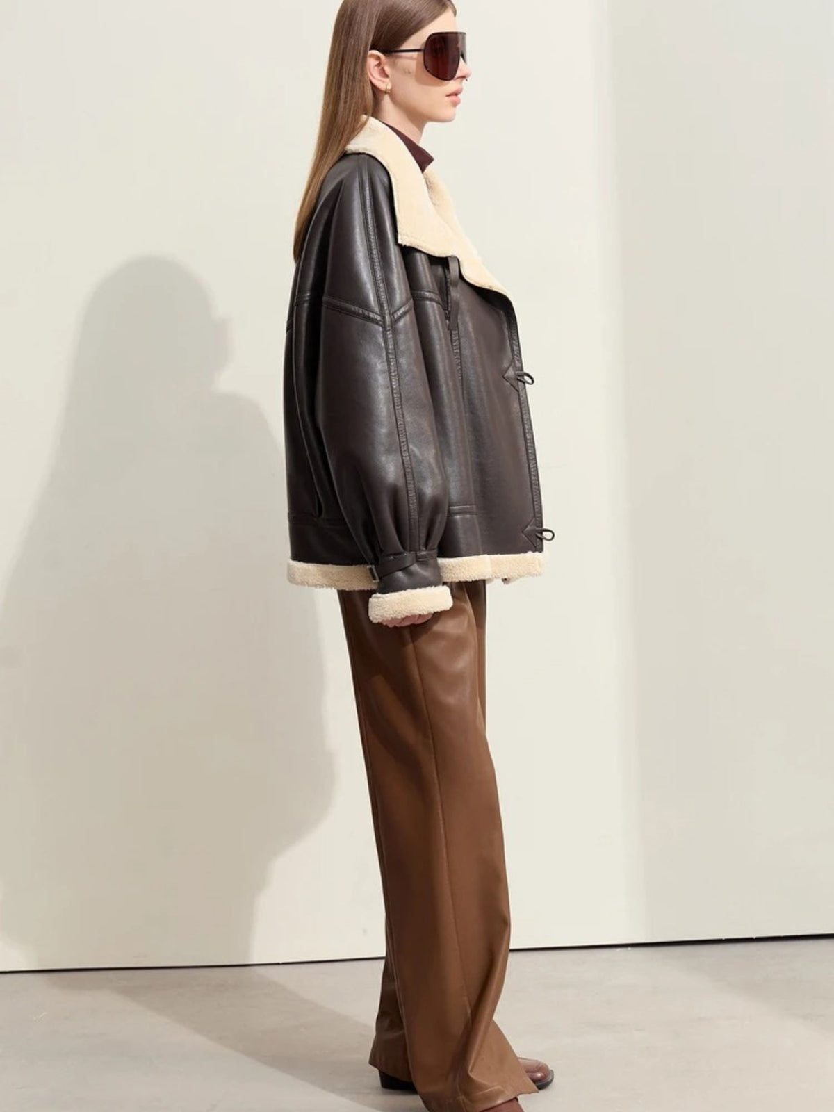 Model wearing aviator jacket and sunglasses, hands in pockets