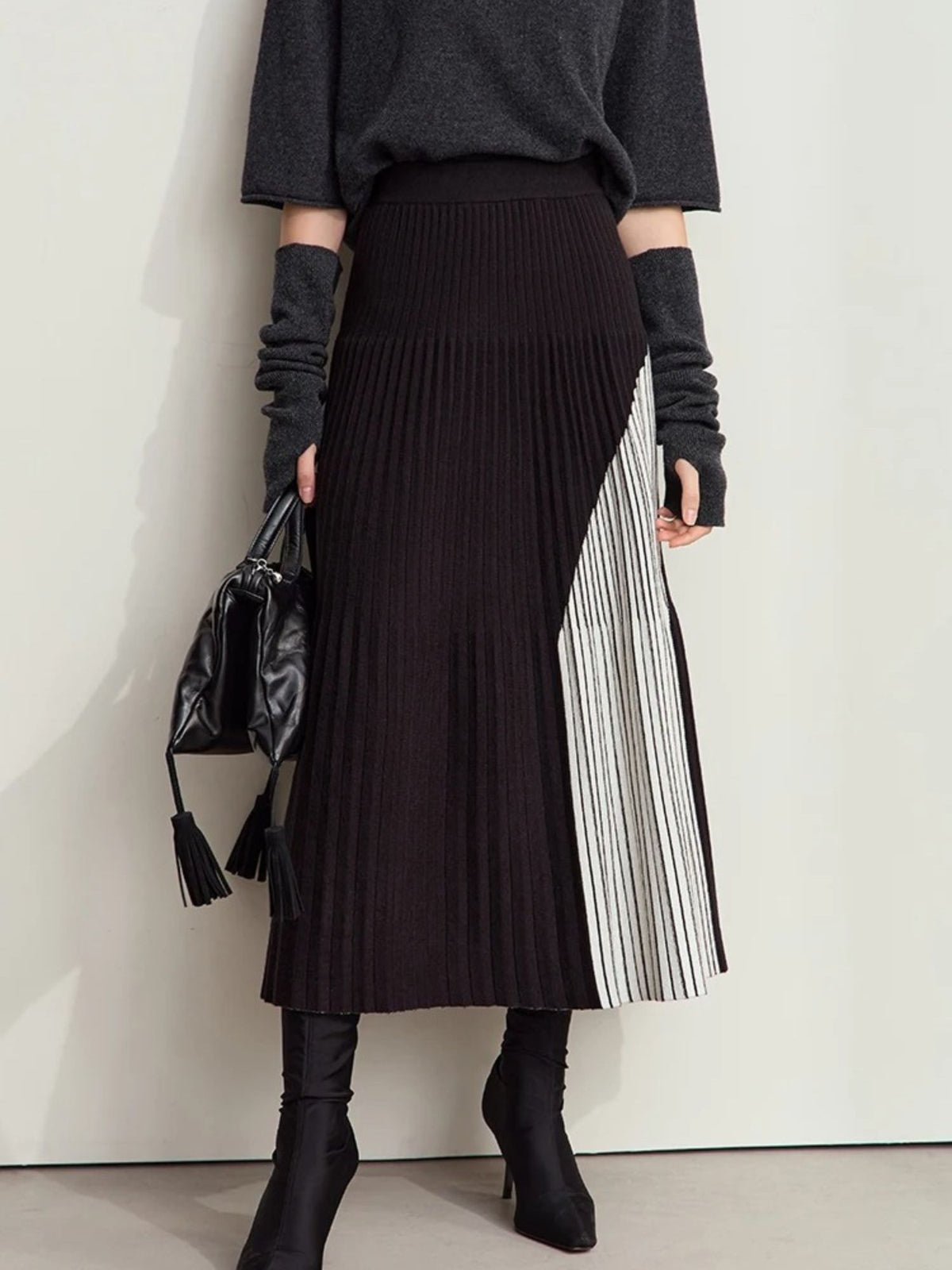 Dark brown pleated skirt with beige contrast panel, worn with black ribbed top and boots