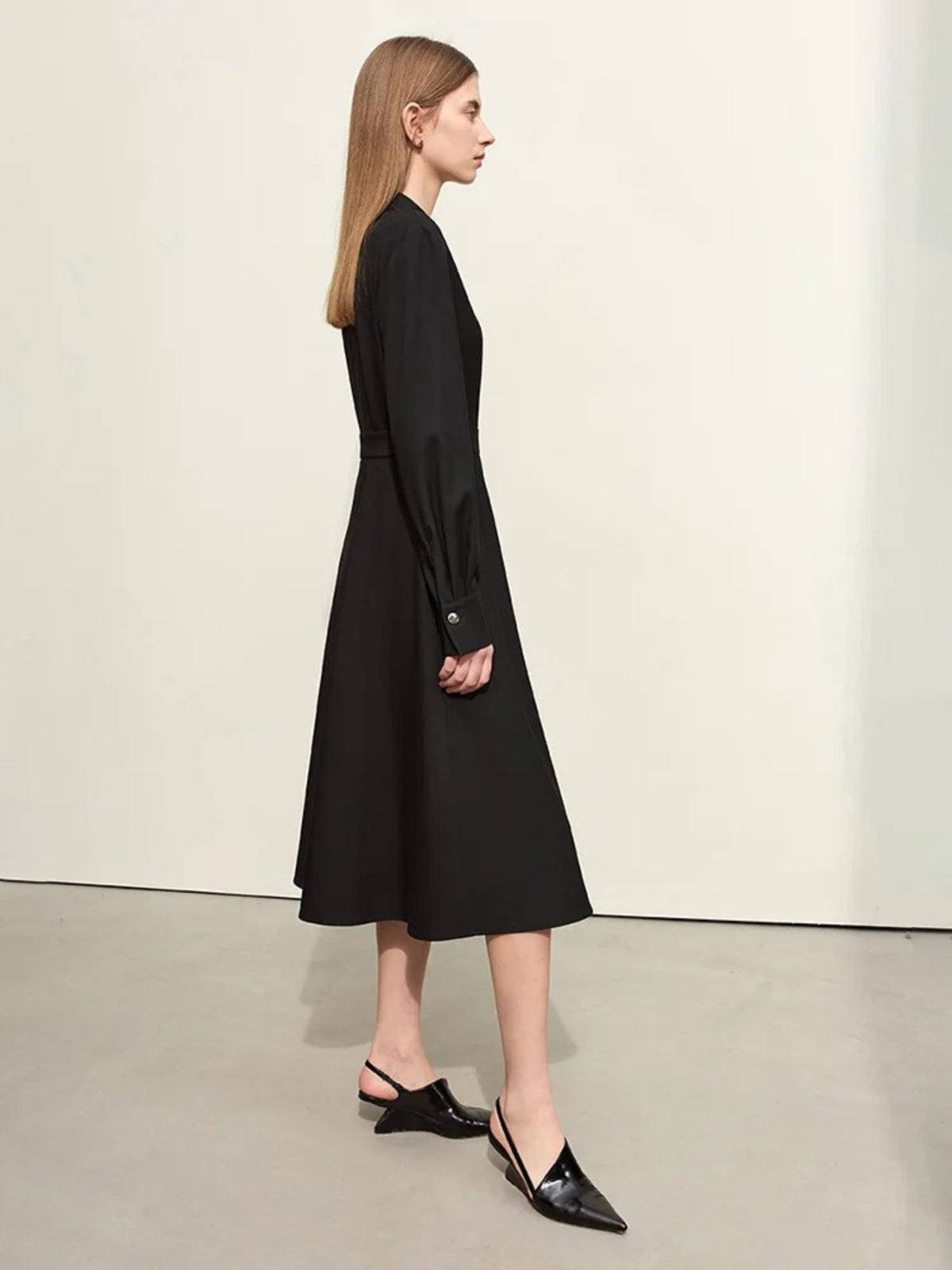 Side view of black midi dress with long sleeves and pointed collar