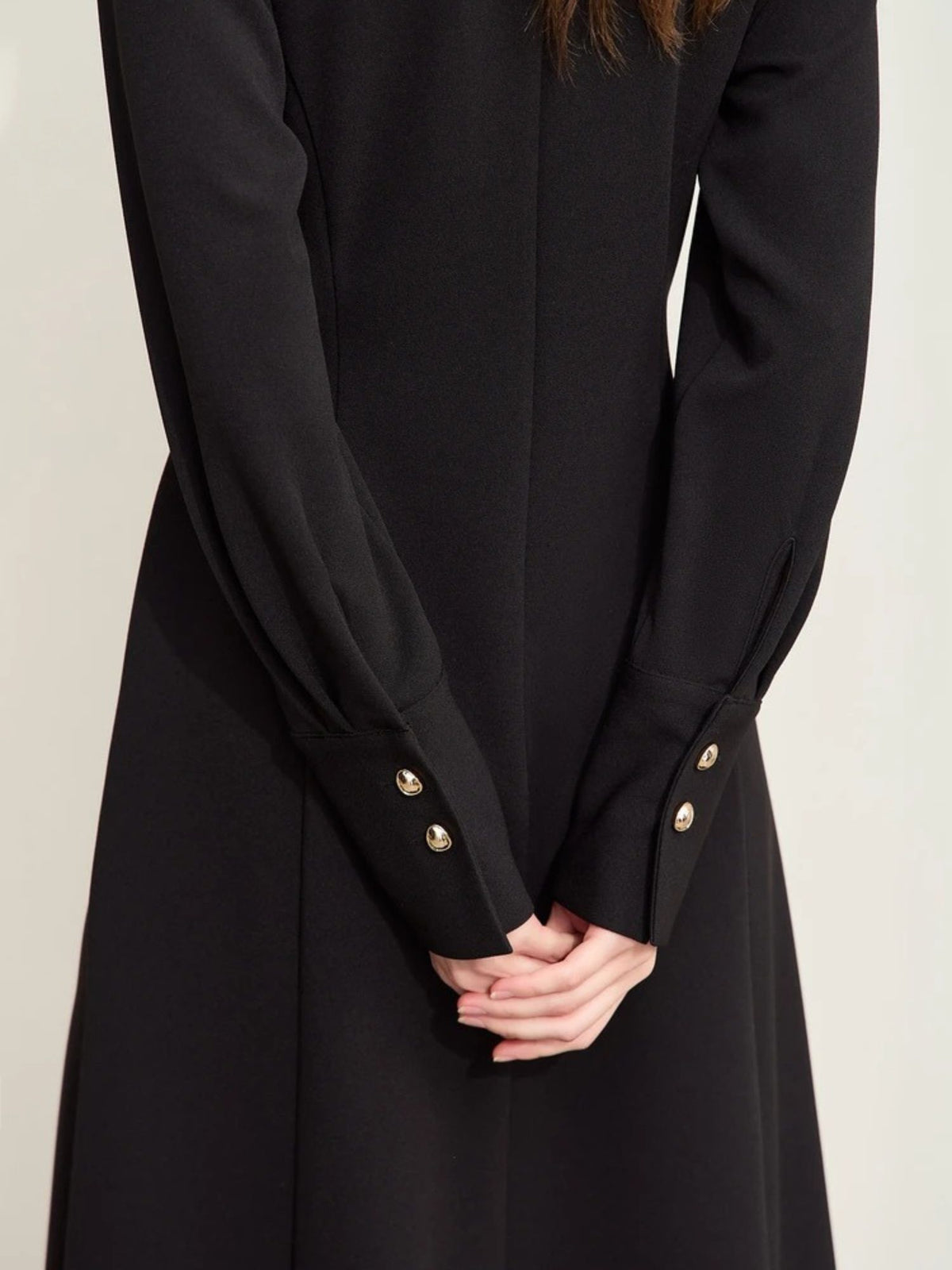 Close-up of black dress sleeve with gold button detail


