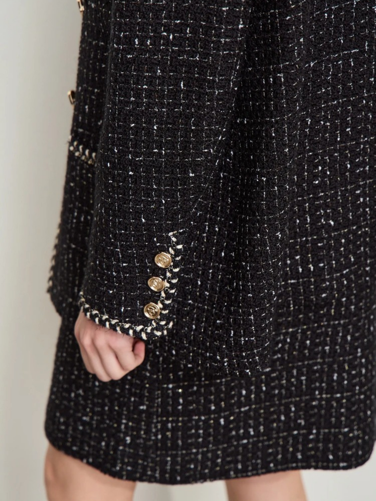 Front view of ivory tweed jacket with gold buttons and front pockets, styled with skirt