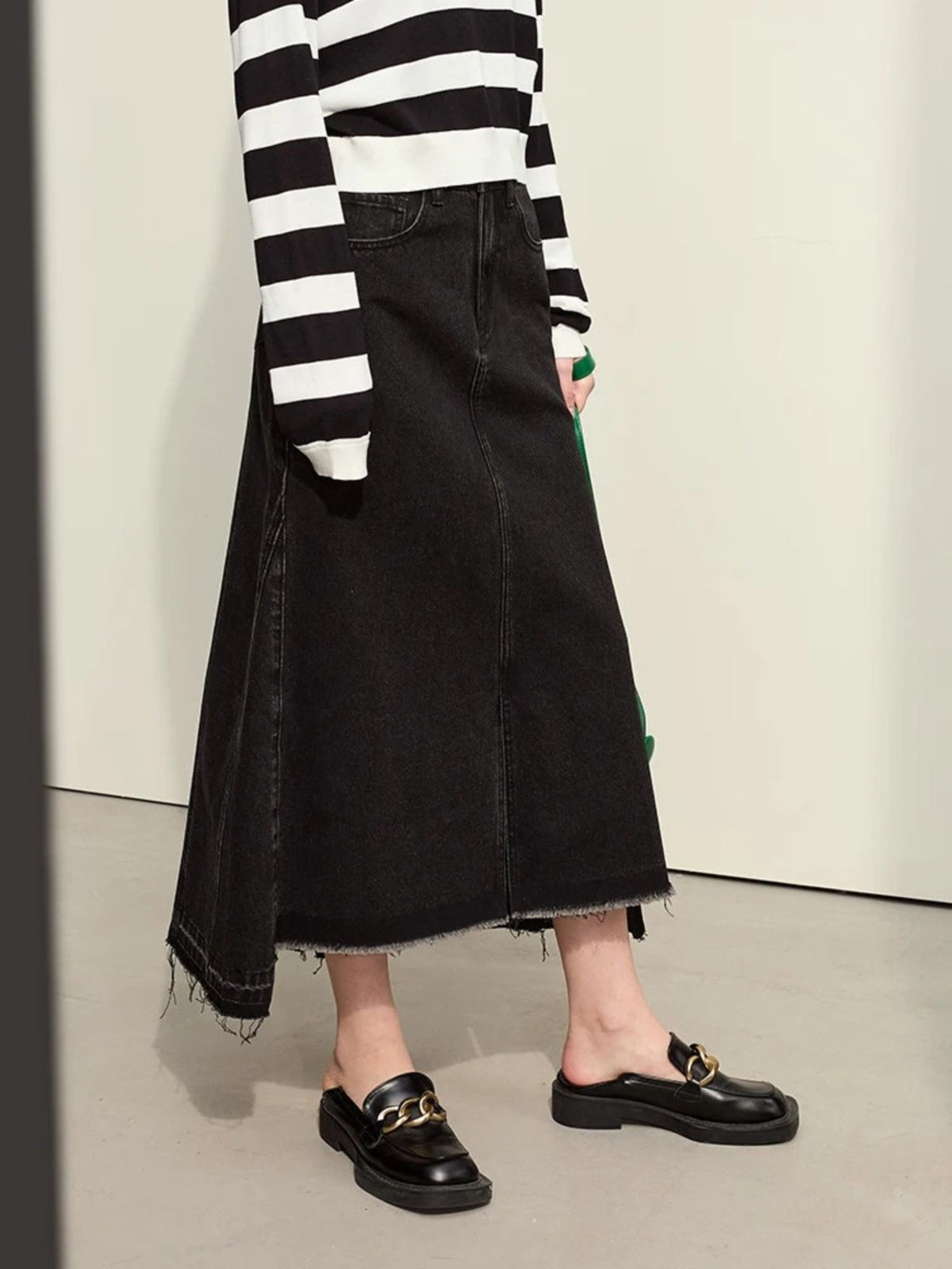 Back view of black midi skirt with subtle pleats, styled with sheer black top

