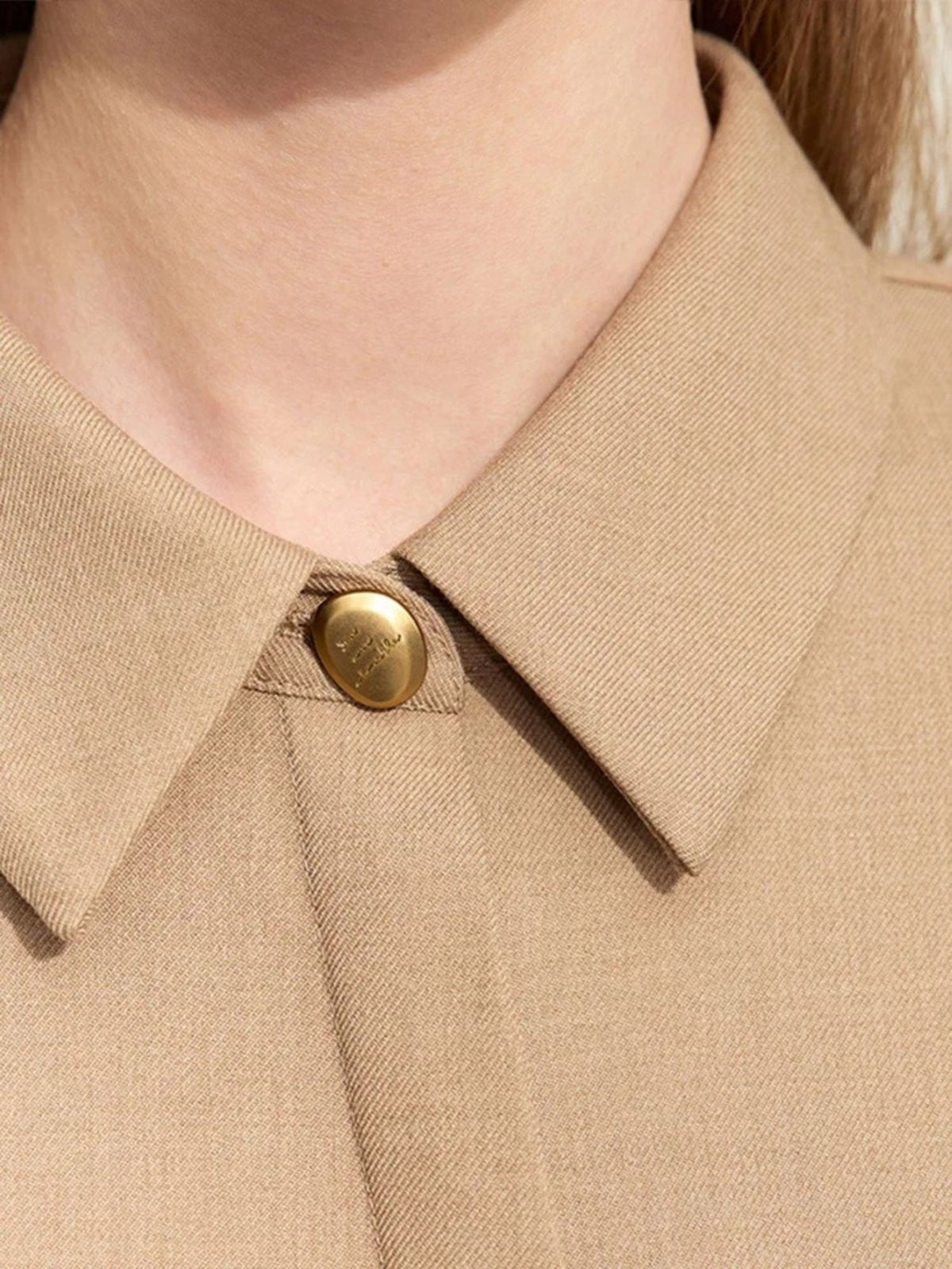 Zoomed-in view of collar and button on camel dress with clean stitching