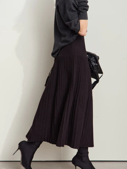Side view of black and beige pleated skirt styled with long-sleeve knit top