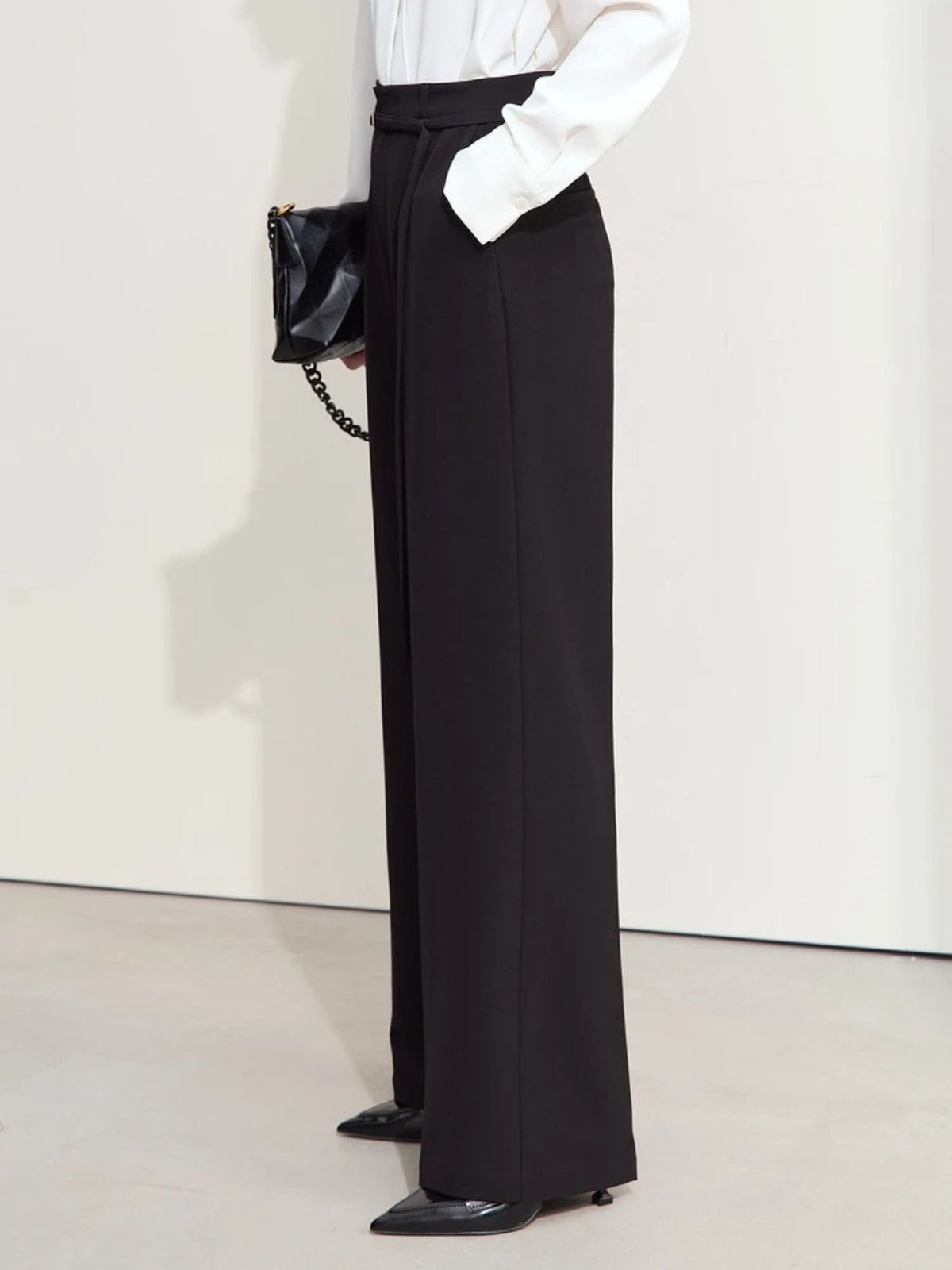 Back view of black trousers with subtle pleats and wide-leg silhouette