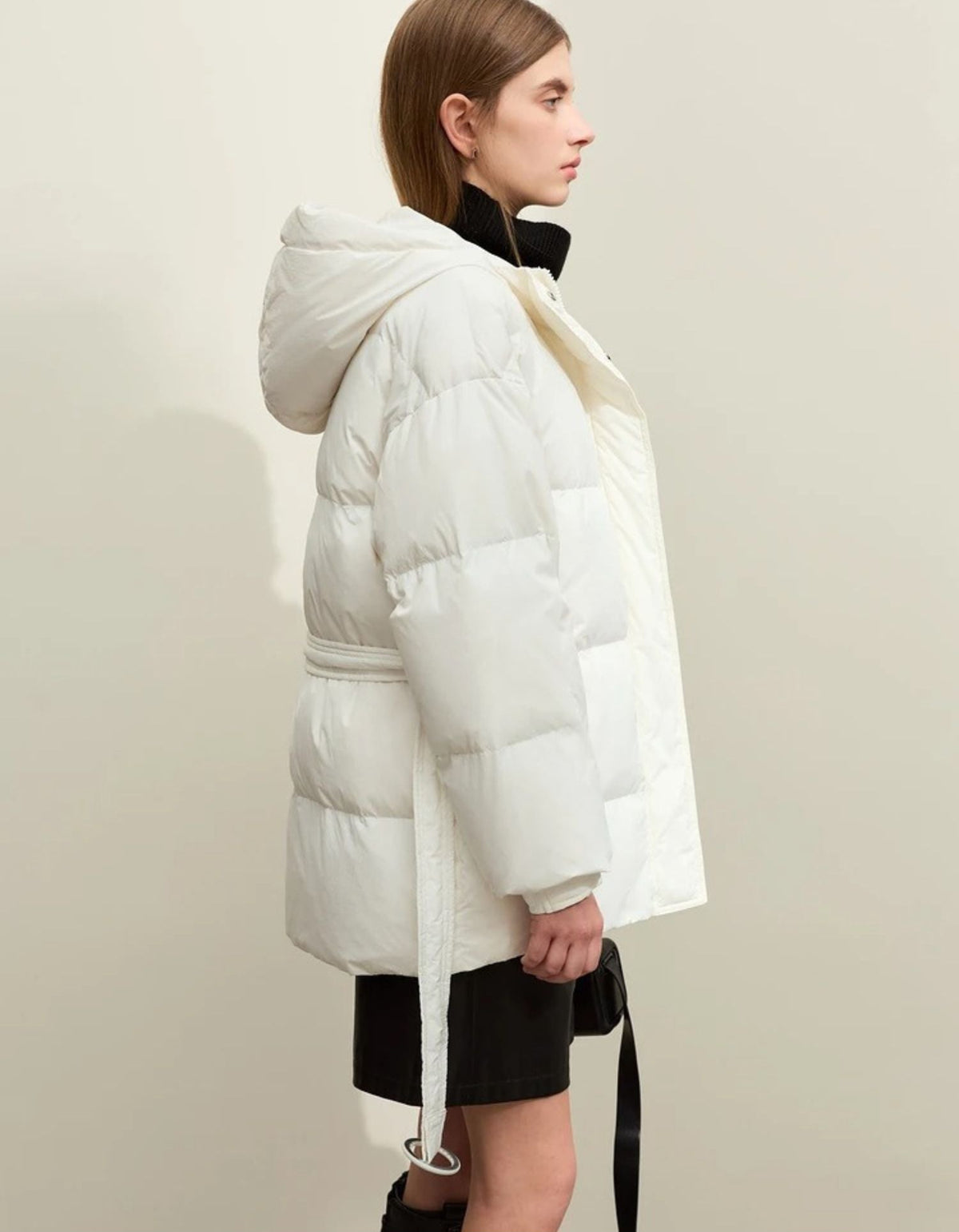 Side profile of white puffer jacket with black zipper detail and padded hood