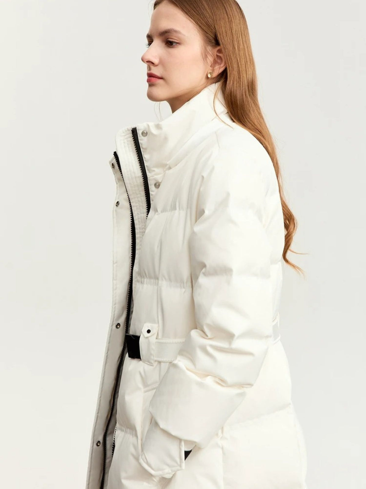 Side profile of model wearing belted white puffer coat with fur-lined hood