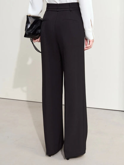 Side-back angle of black trousers with soft drape and ankle-length hem