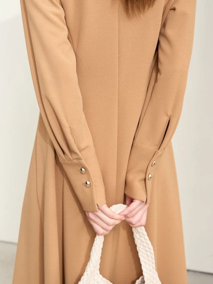 Close-up of camel dress sleeves with gold buttons and gathered cuffs