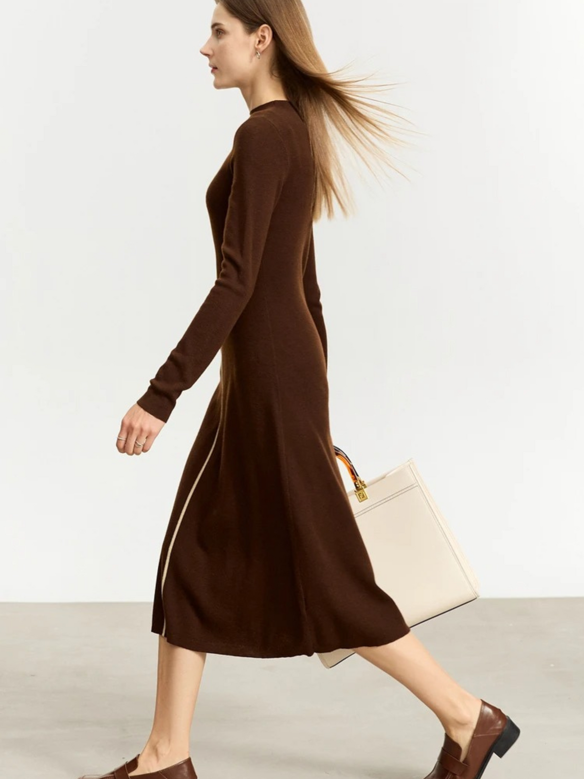 Model walking in brown zip midi dress with fitted sleeves and mid-length hem