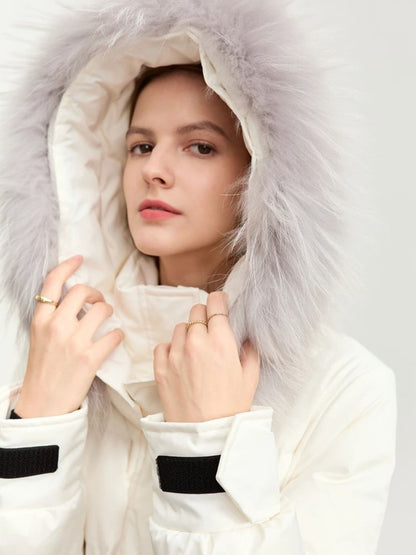 Model with hood up wearing white puffer coat, hands adjusting collar