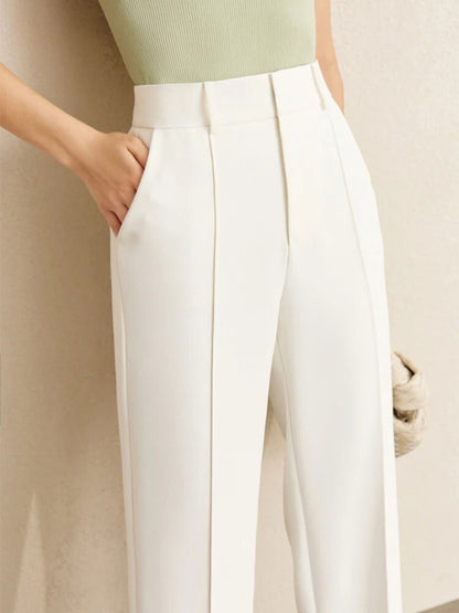 High-waisted white trousers with pleated front, styled with green ribbed top