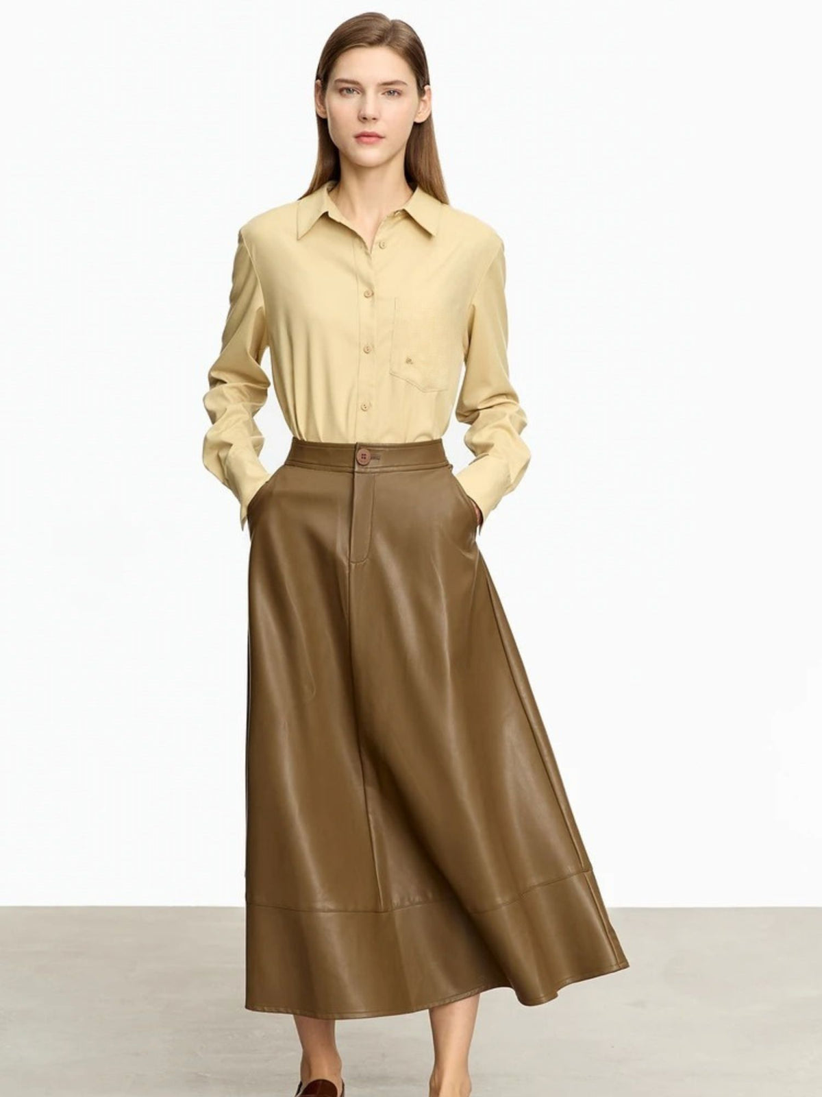 Woman wearing a beige shirt and brown leather skirt on a white background