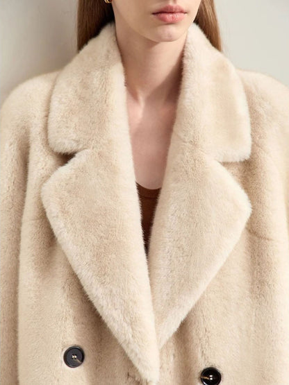 Close-up of a person wearing a beige coat with a neutral background